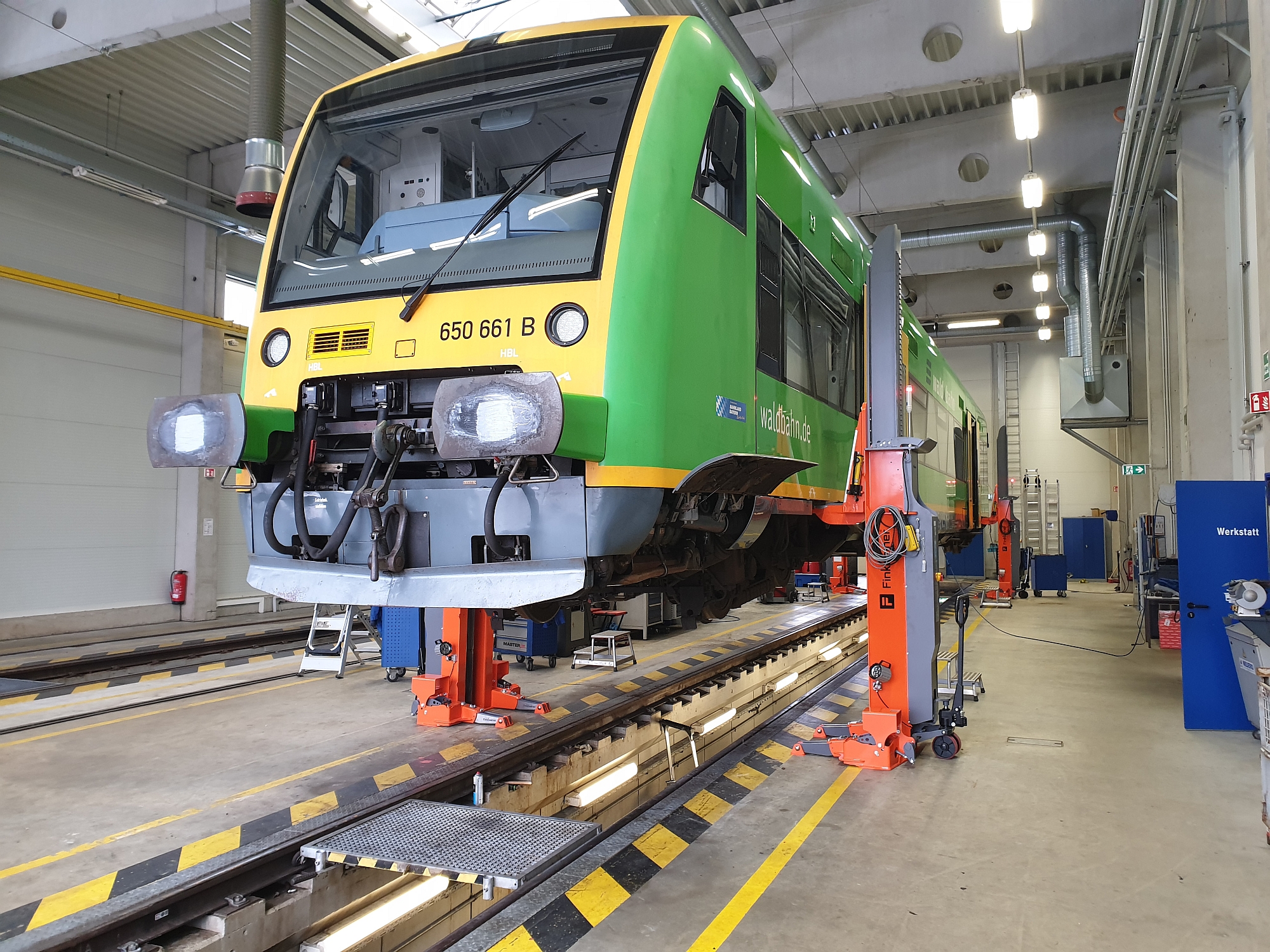 Mobile lifting hoists equipped with adjustable load brackets with a tramway in a railway workshop.